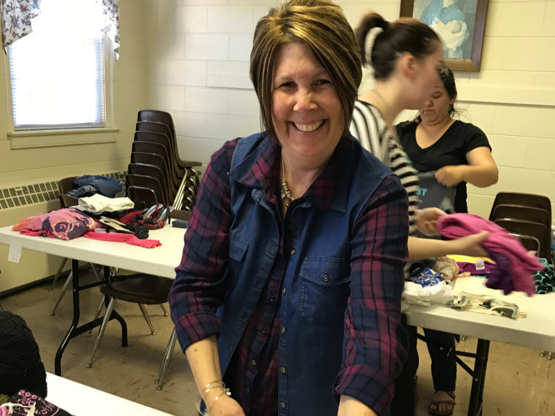 a woman sorting clothing at a table